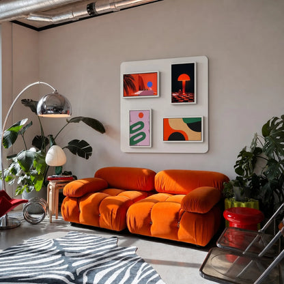 Pintura smart gallery wall system displaying colorful abstract art in a modern living room with an orange sofa.